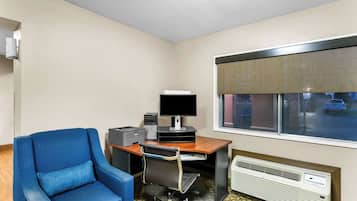 Ein Hotelzimmer mit Schreibtisch, Computer, Stuhl, Fenster mit Blick und Klimaanlage.