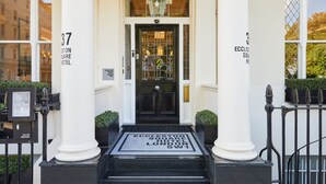 The entrance to the Eccleston Square Hotel with a black door, white columns, and a black metal gate. - Eccleston Square Hotel (London)