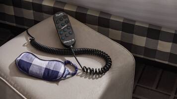 A checkered bedspread, a coiled telephone cord, and a blue and white pillow on a cushioned surface.