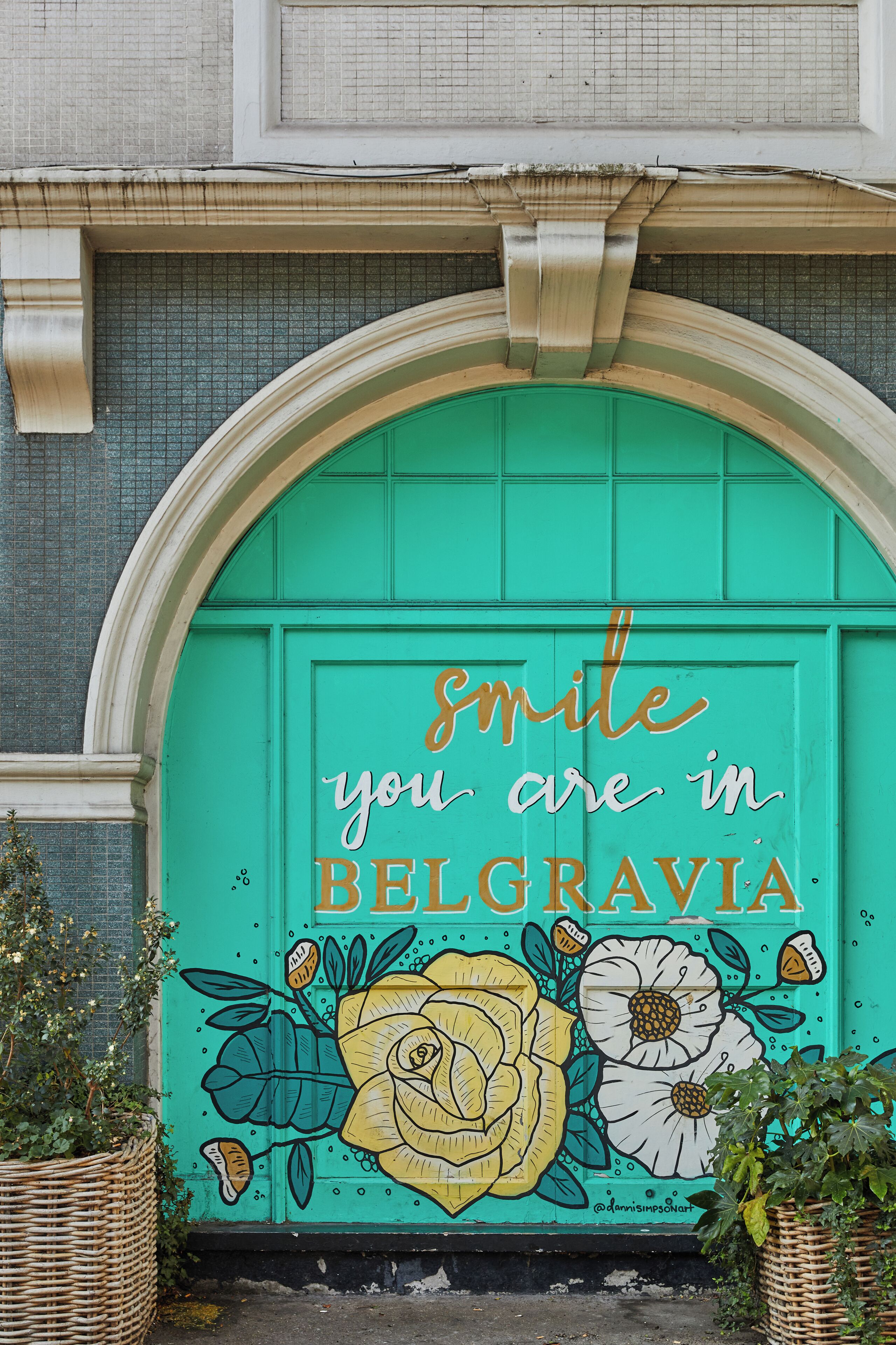 A turquoise door with a floral mural and the text 'smile you are in BELGRAVIA' in gold lettering.