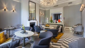 A modern living room with a chandelier, sofas, a coffee table, and a fireplace. - Eccleston Square Hotel (London)