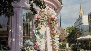 A building with a curved facade, a sign reading 'PORSCHEN cafe,' and a floral arrangement. - Eccleston Square Hotel (London)