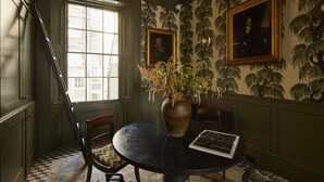 A room with a round table, a vase with flowers, and two framed portraits on the wall. - Georgian House Hotel (London)