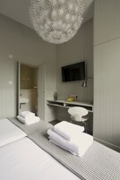 Una habitación de hotel moderna con una cama grande, un escritorio, un televisor y un baño visible a través de una puerta abierta.