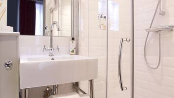Une salle de bain moderne avec une douche à parois de verre, un lavabo blanc et une serviette suspendue à un porte-serviettes.