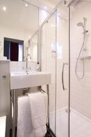 Ein modernes Badezimmer mit einer einteiligen Duschkabine, einem weißen Waschbecken und einem Handtuch auf einem Haken.