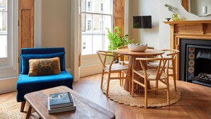 A cozy living room with a blue sofa, wooden coffee table, and a fireplace. - Georgian House Hotel (London)