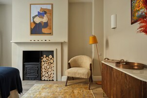 Ein Wohnzimmer mit Kamin, einer Couch, einem Sessel, einer Lampe und einem dekorativen Teppich.