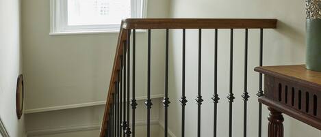 Una scala in legno con ringhiera nera e un lampadario sopra.