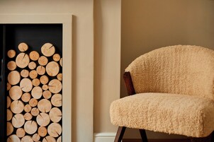 Ein Zimmer mit einer Wand-Installation aus Holz und einem komfortablen, strukturierten Sessel.