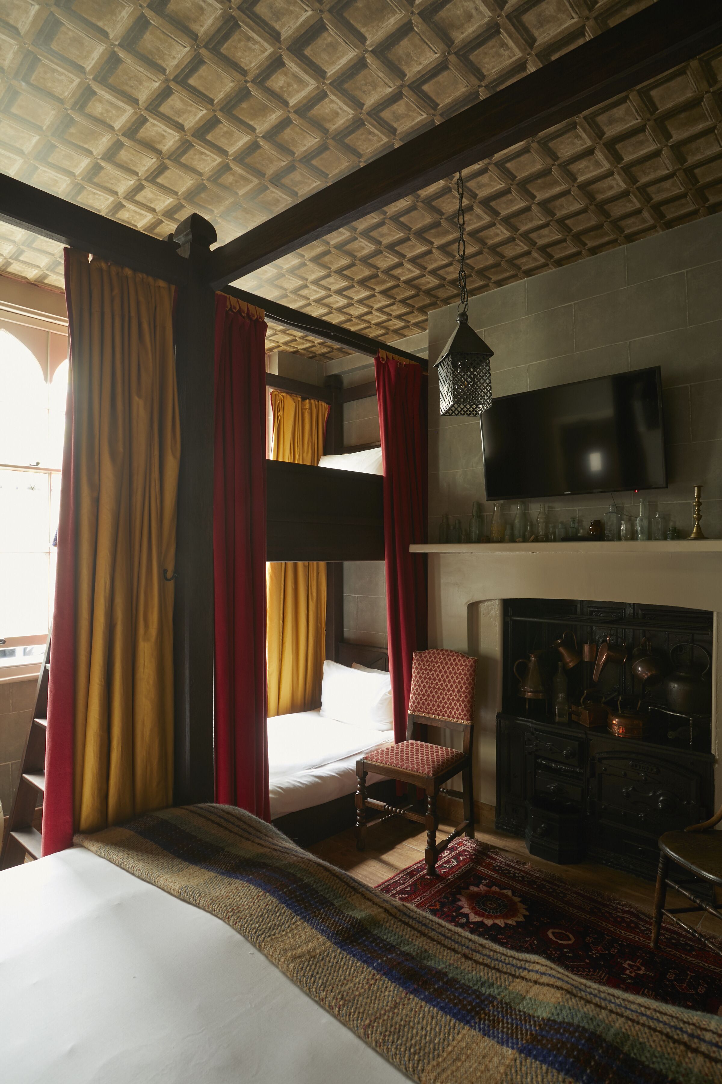 A room with a bunk bed, a fireplace, a television, and a patterned rug.
