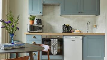 Een keuken met blauwgroene kastjes, een magnetron, een koffiezetapparaat, een broodrooster, een spoelbak en een vaatwasser.