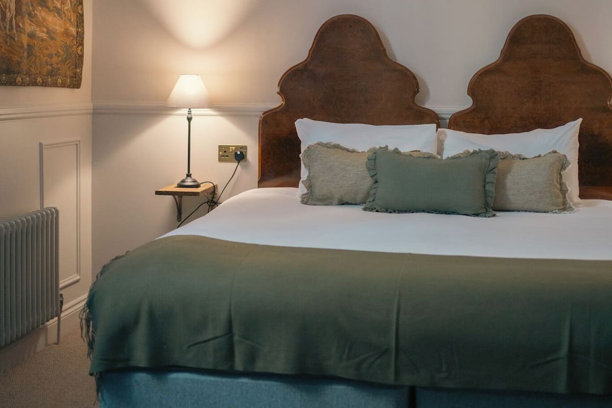 A bedroom with a bed, a nightstand, a lamp, and a hanging light fixture.