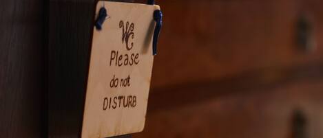 A wooden sign with the text "We Please do not DISTURB" attached to a wooden surface.