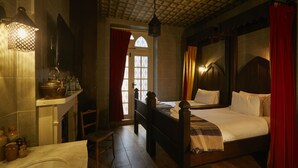A traditional room with a wooden bed, a small table, and a chair. There is a window with a view of the outside. - Georgian House Hotel (London)