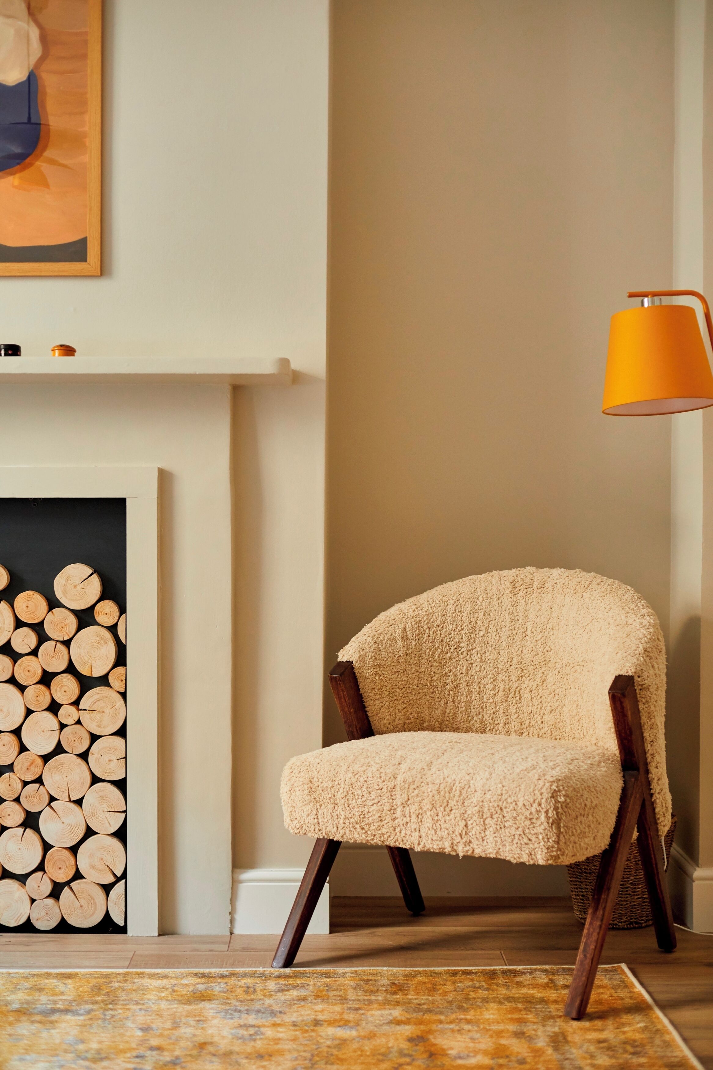 Une pièce chaleureuse avec un fauteuil, une cheminée et une lampe.
