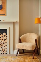 Una habitación acogedora con una silla, una chimenea y una lámpara.