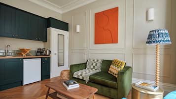 Un salon avec un canapé vert, une table basse en bois et une lampe.