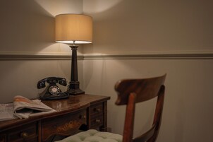 Ein Holztisch mit einer Lampe, einem Wählscheibentelefon und einem Stuhl.