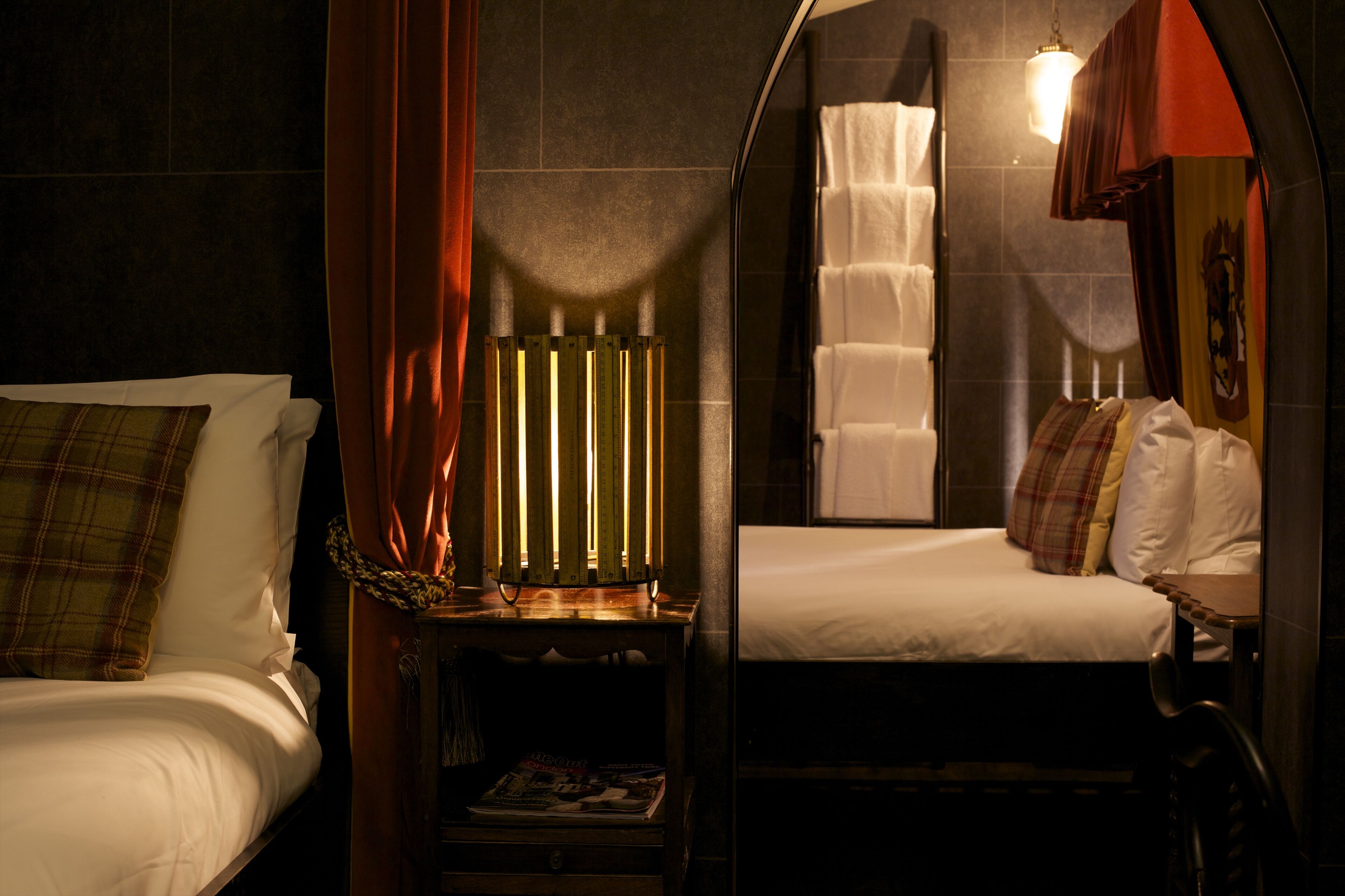 A room with a bed, a nightstand with a lamp, and a window with curtains.