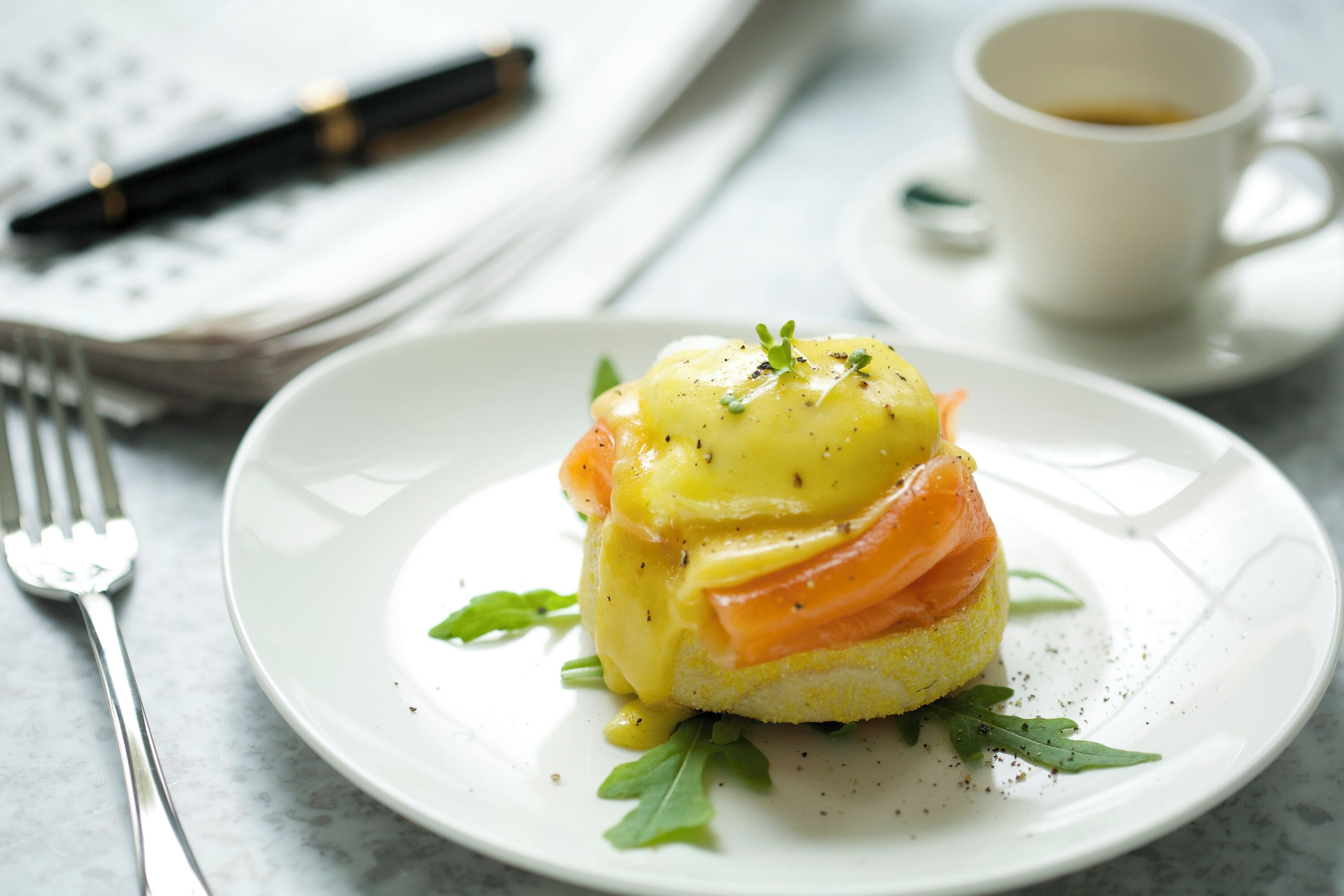 Ein Teller mit Räucherlachs und Sauce Hollandaise, garniert mit Kräutern, auf einem weißen Teller.