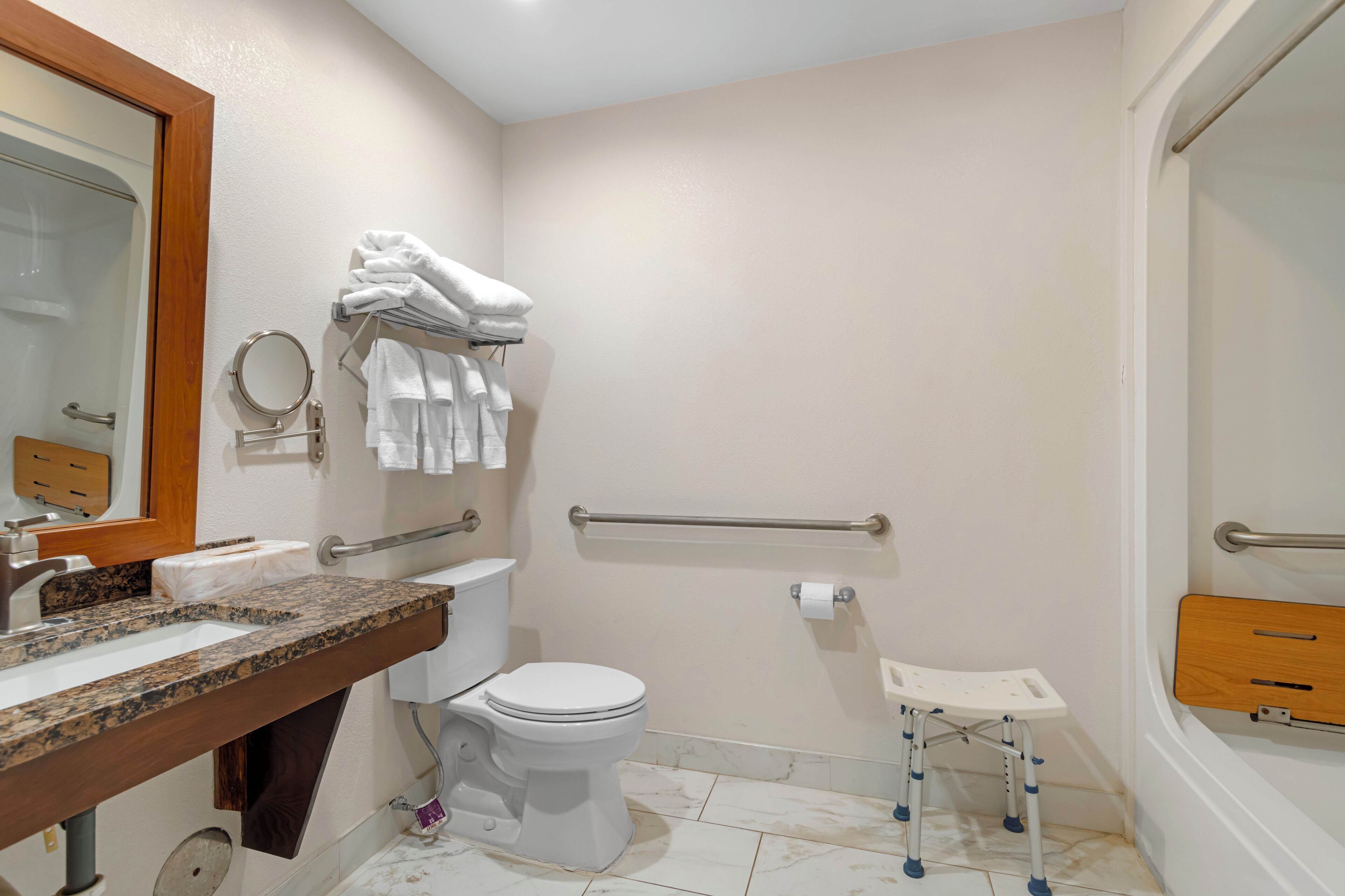 A bathroom with a toilet, sink, and handrails.