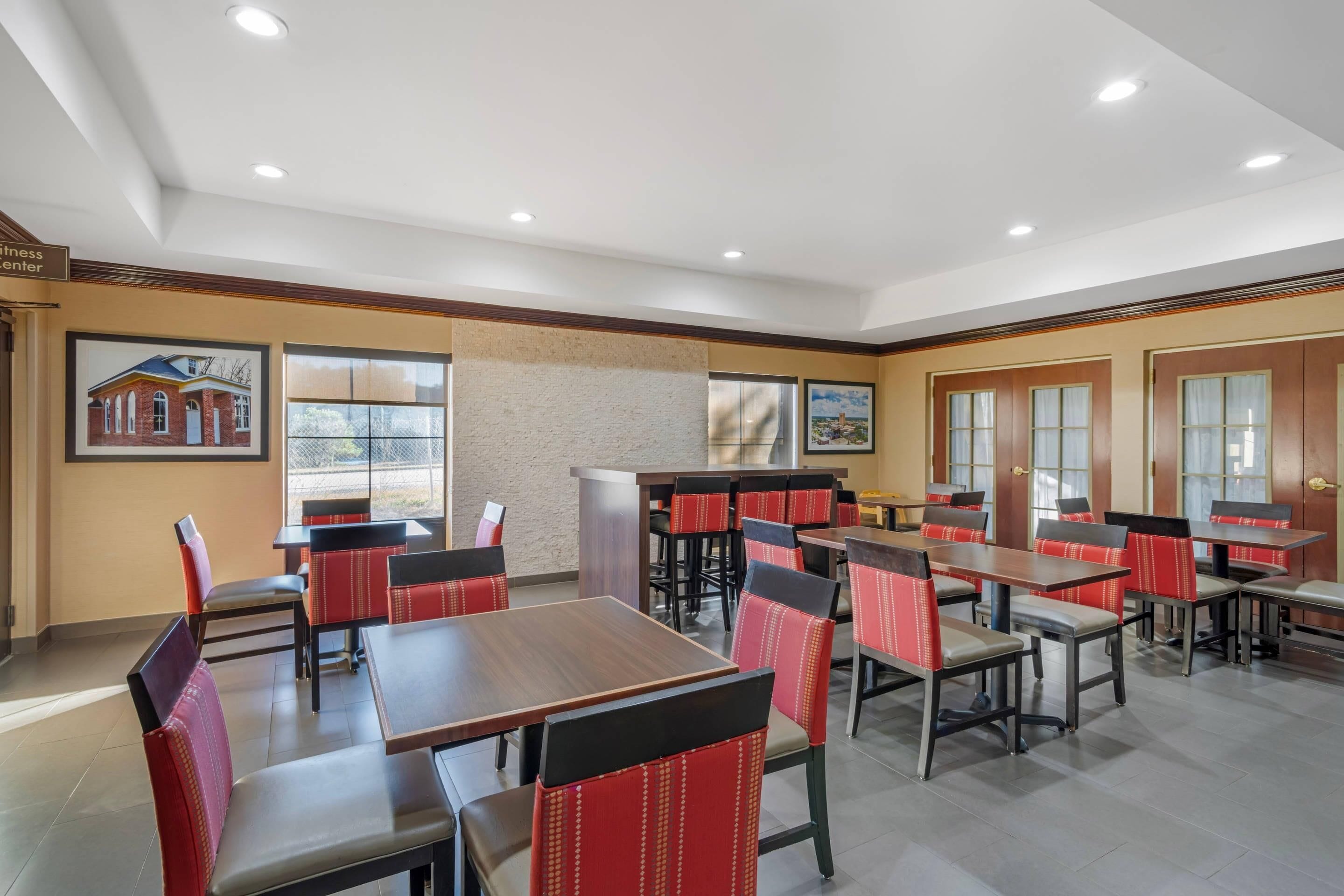 A spacious dining area with multiple tables and chairs, a reception desk, and framed pictures on the walls.