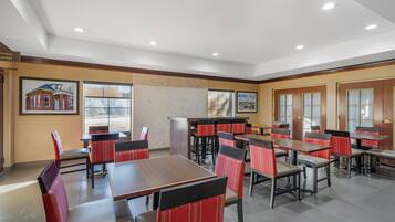 A spacious dining area with multiple tables and chairs, a reception desk, and framed pictures on the walls.