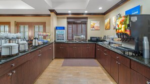 Eine Hotelküche mit einer Buffet-Anrichtung, inklusive einer Kaffeestation, einem Kühlschrank und einer Mikrowelle.