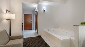 Ein modernes Badezimmer mit einer großzügigen Badewanne, einem Sessel und einer Stehlampe.