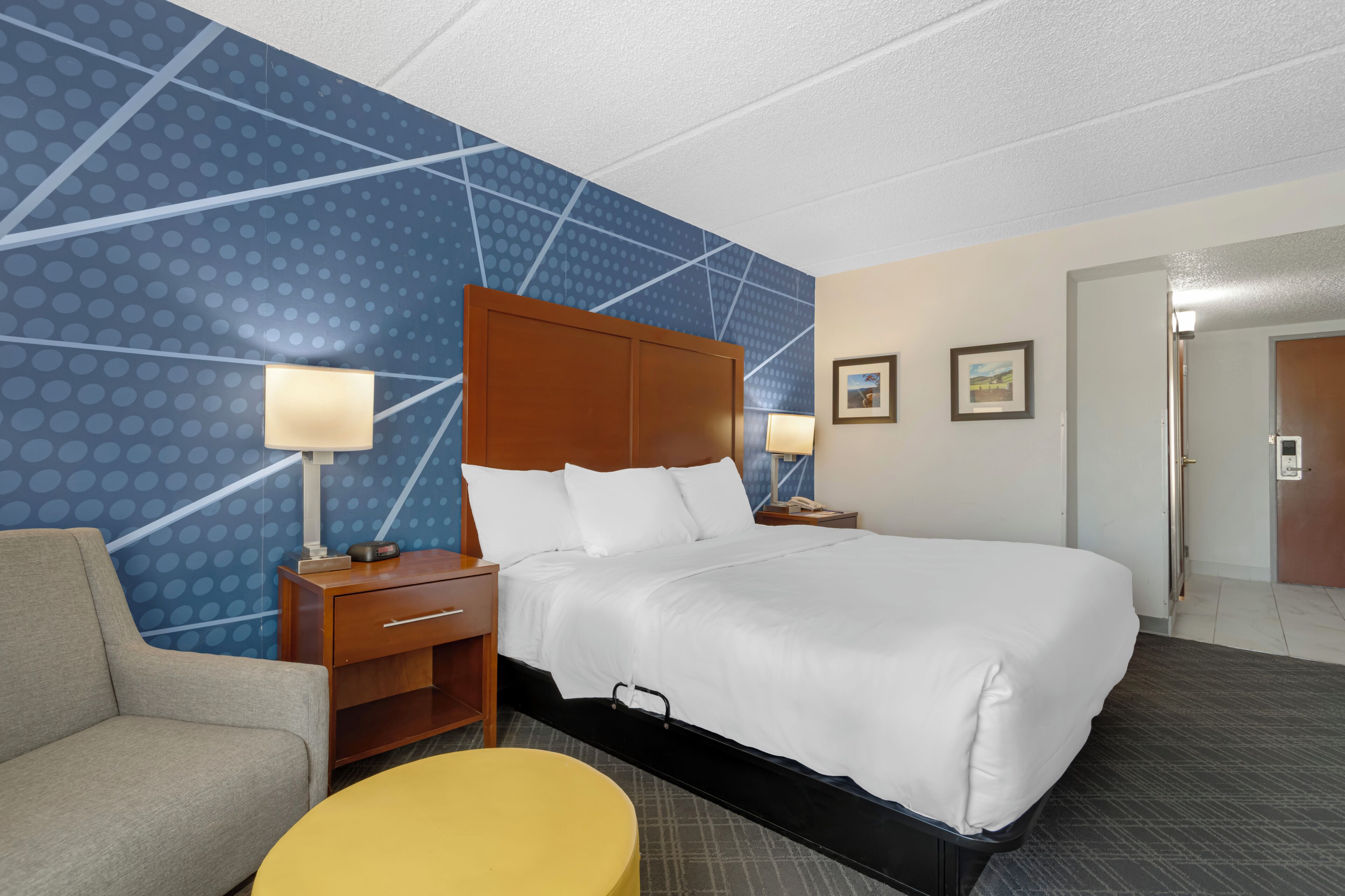 Una habitación de hotel con una cama grande, una mesita de noche, un escritorio, una silla y una pequeña mesa.