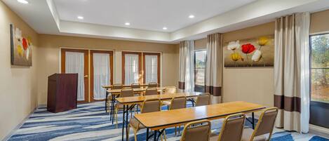 Un salón de conferencias con alfombra de diseño azul, paredes beige y un amplio ventanal con cortinas.