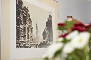 A framed black and white photograph of a cityscape with buildings and a statue.