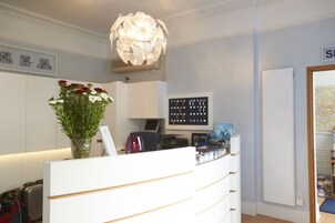 Un mostrador de recepción con un jarrón de flores, una computadora y una pantalla mural.