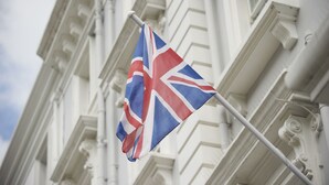 Un asta con una bandera, frente a un edificio de arquitectura clásica.