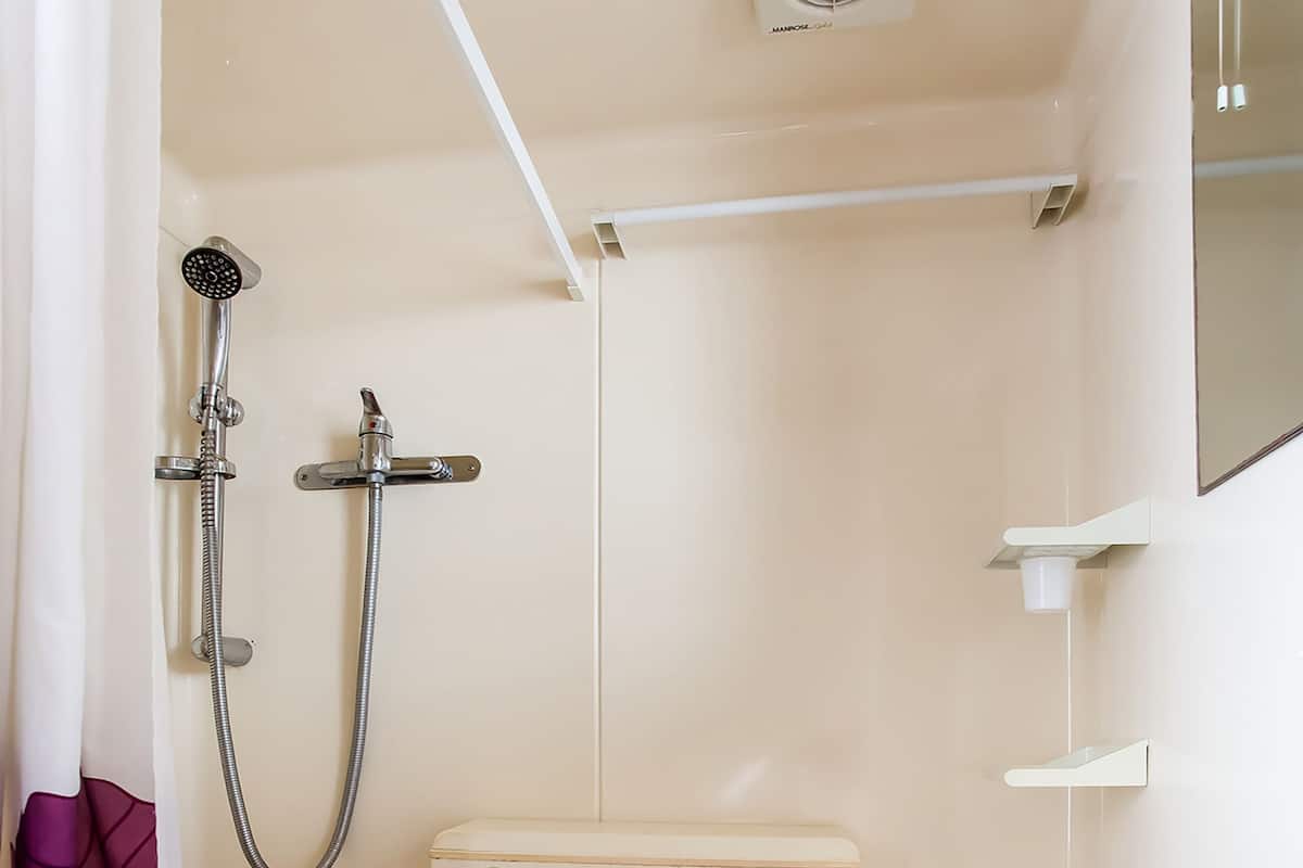 Baño pequeño y funcional con inodoro, lavabo y ducha.