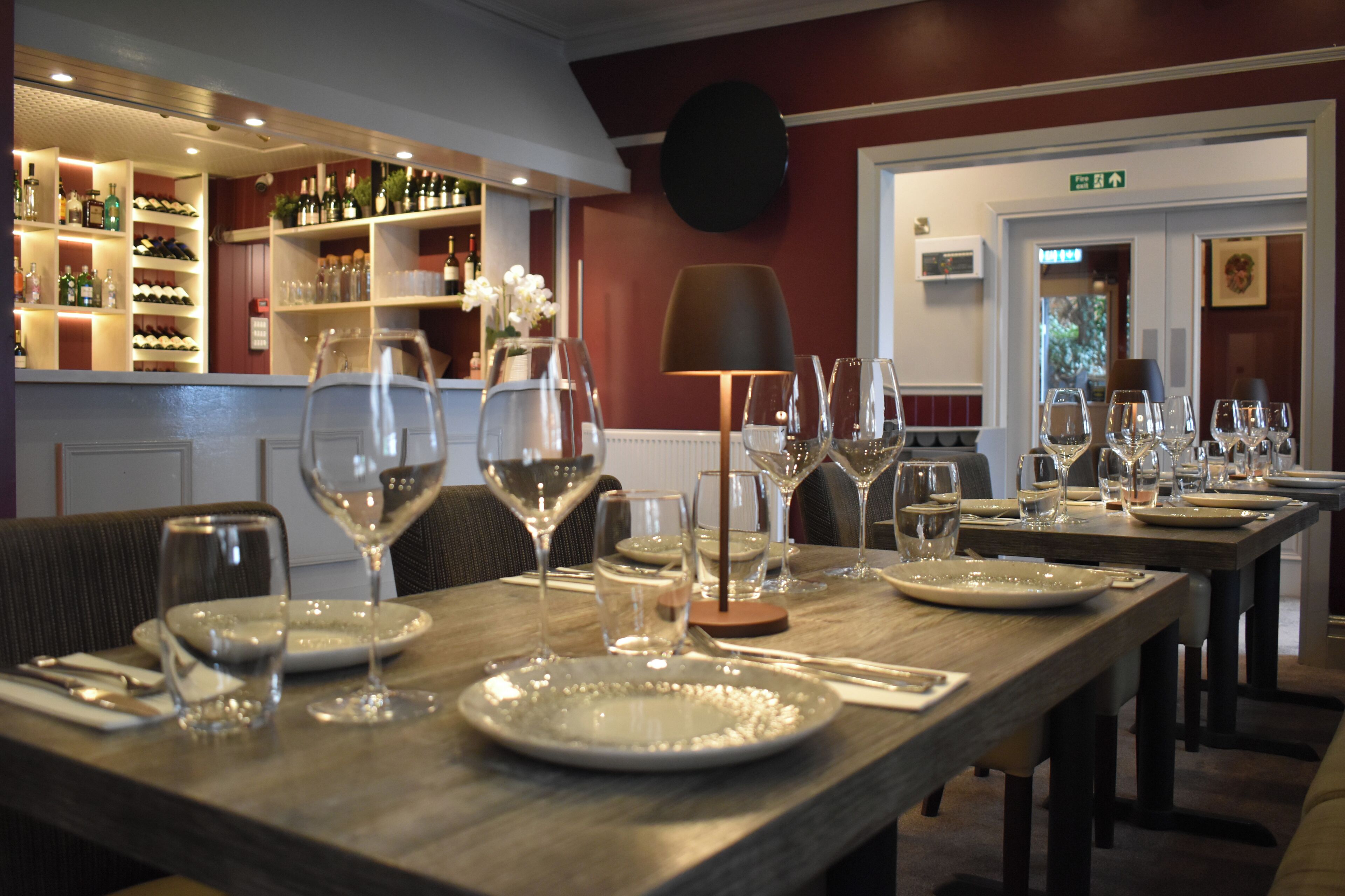 Een restaurant met een bar, houten tafels en stoelen.
