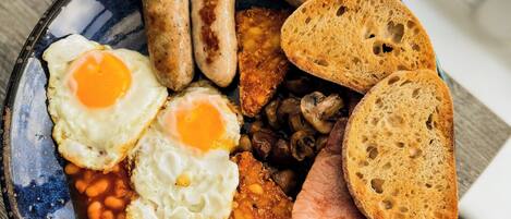 A bowl of breakfast with eggs, sausages, beans, and toast.