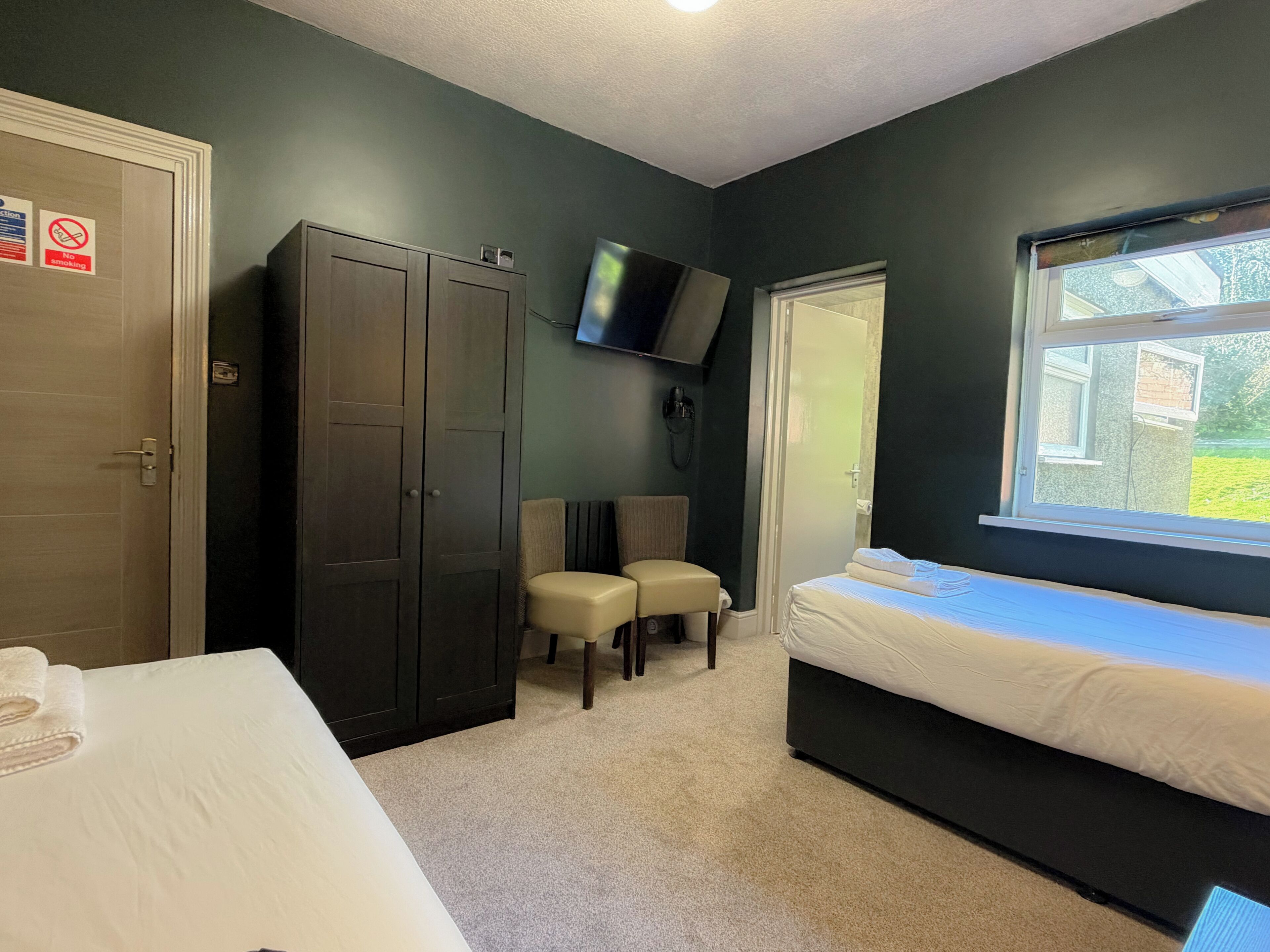 A hotel room with a bed, a wardrobe, a seating area, a television, and a window.