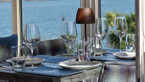 Una mesa de comedor con varias copas de vino y platos, con vistas panorámicas al exterior a través de una ventana.
