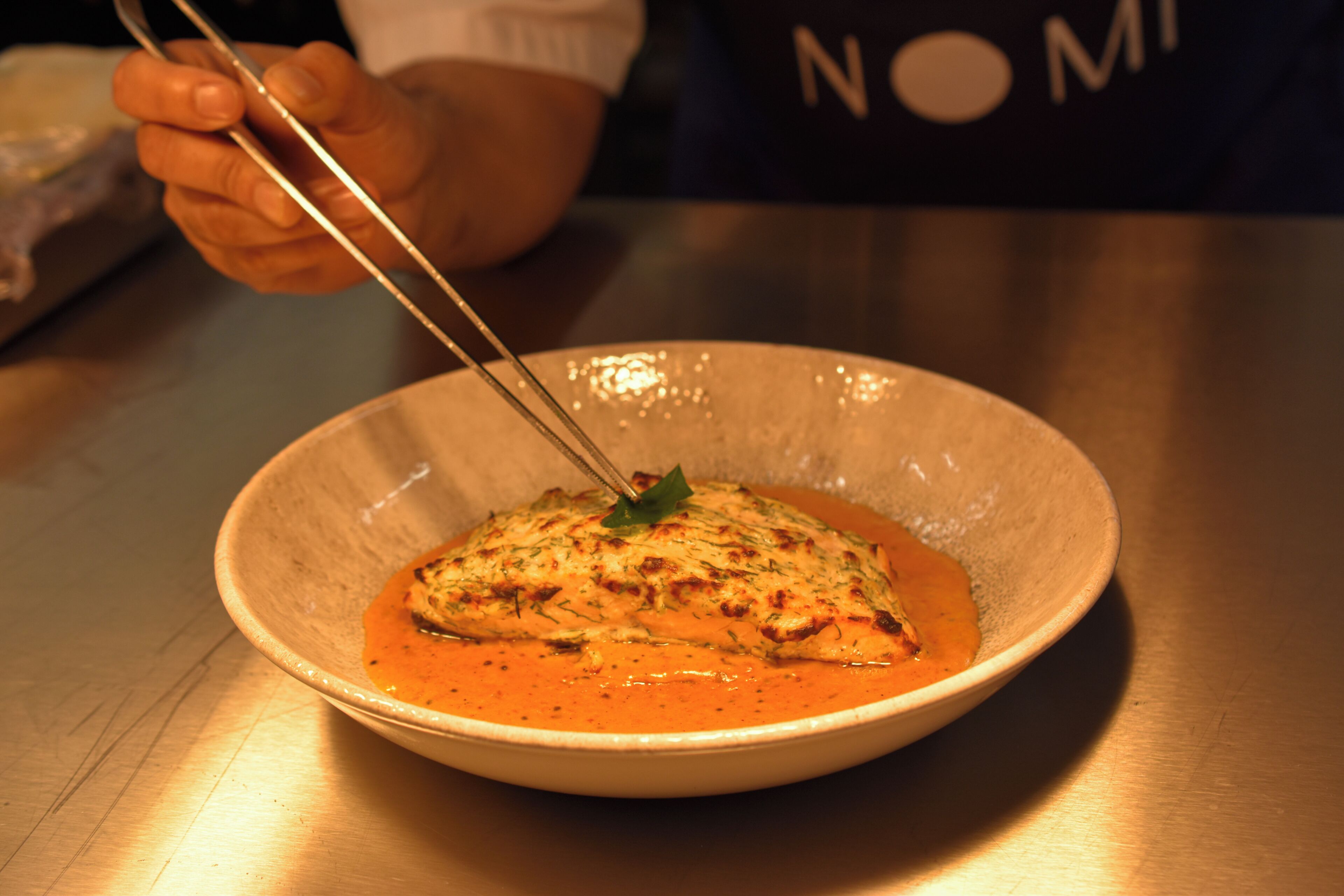 A bowl of food with a fork, on a table.