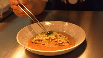 A bowl of food with a fork, on a table.