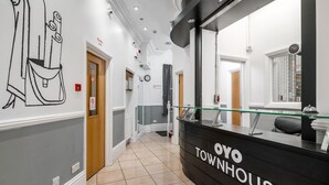 Un espace d’accueil avec un comptoir noir portant l’inscription « OYO TOWNHOUSE », une vitrine et un grand miroir.