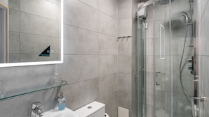 Une salle de bain moderne avec une douche à parois de verre, un lavabo blanc et des toilettes.