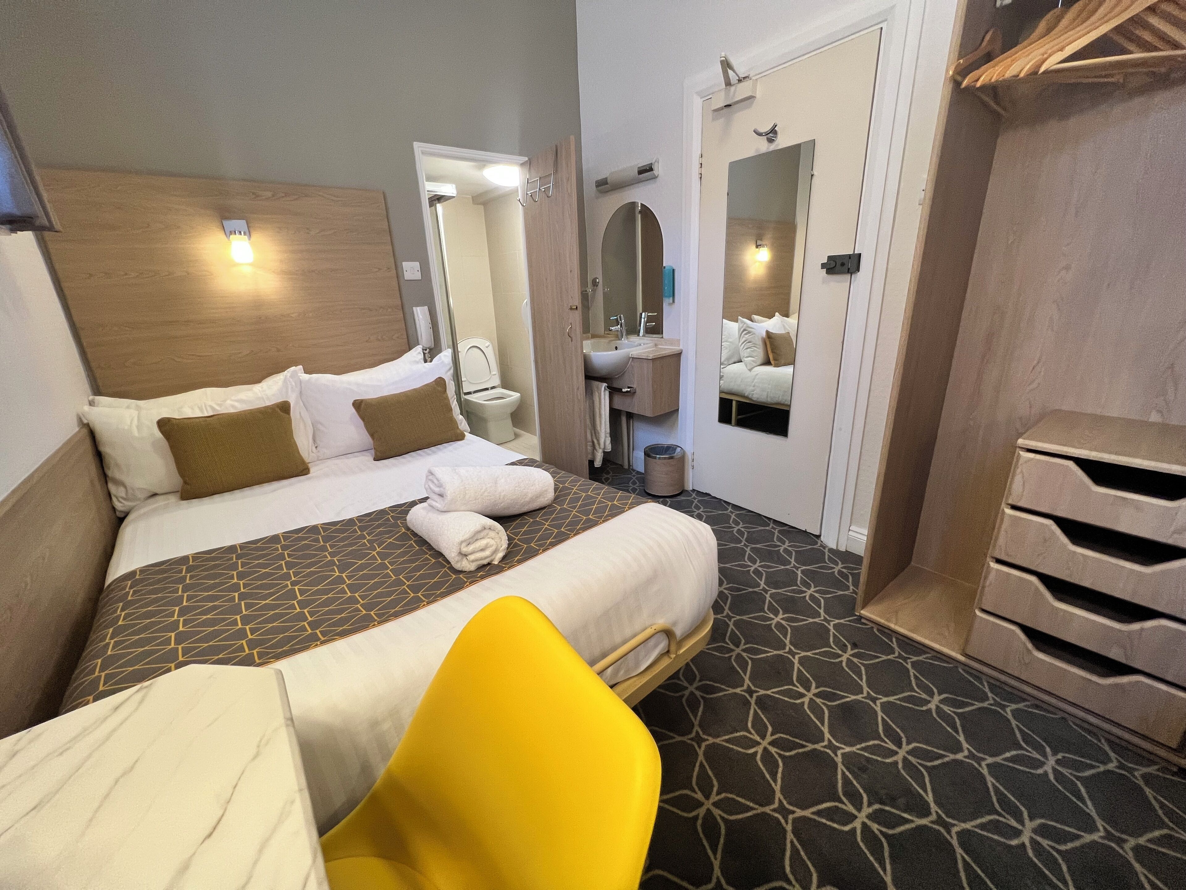 A hotel room with a bed, a bathroom, and a mirror.