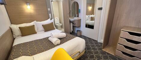 A hotel room with a bed, a bathroom, and a mirror.