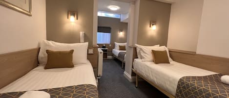 Une chambre d’hôtel avec deux lits simples, un petit bureau et un miroir.