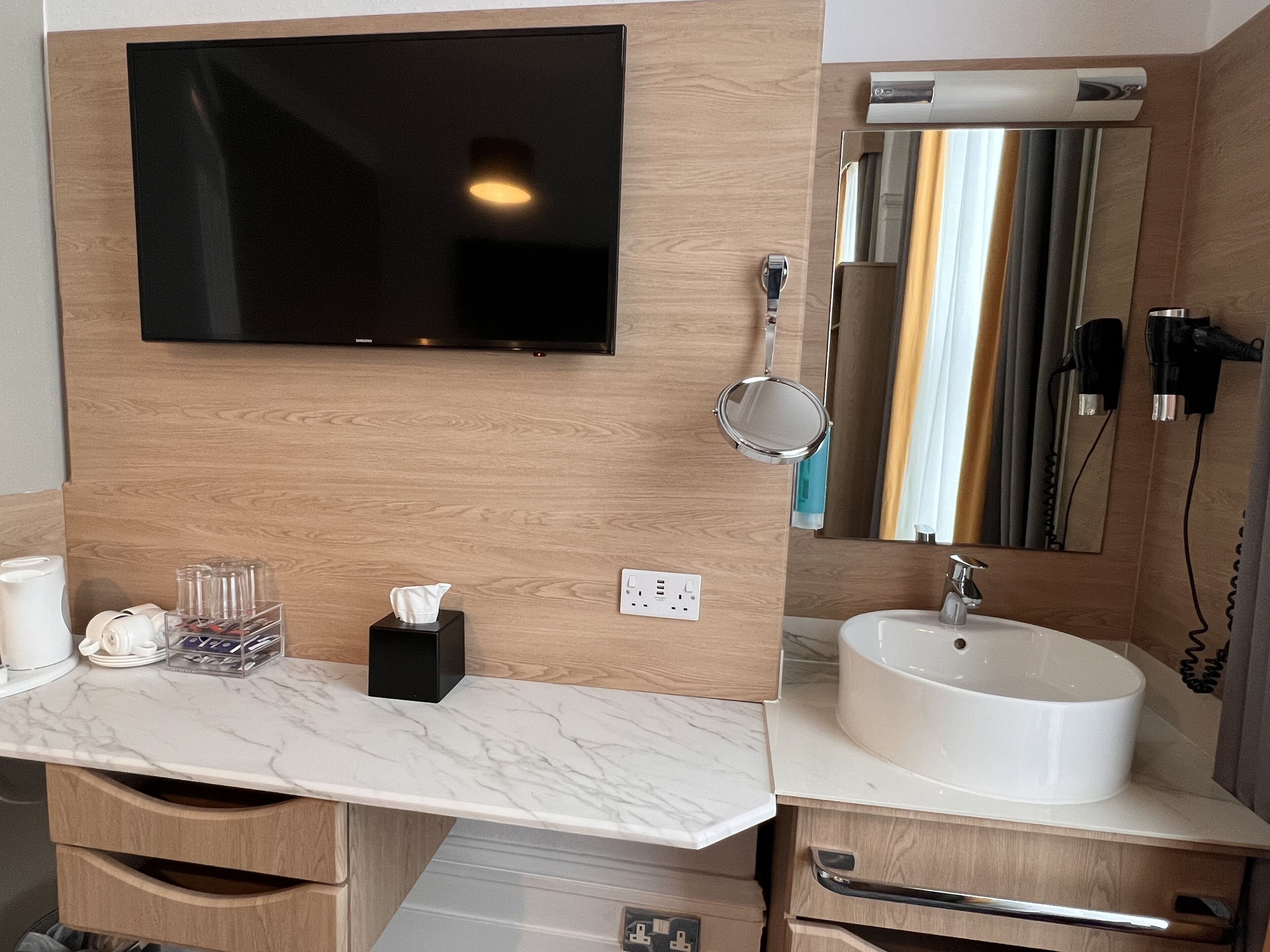 A modern bathroom with a large mirror, a sink, and a toilet.