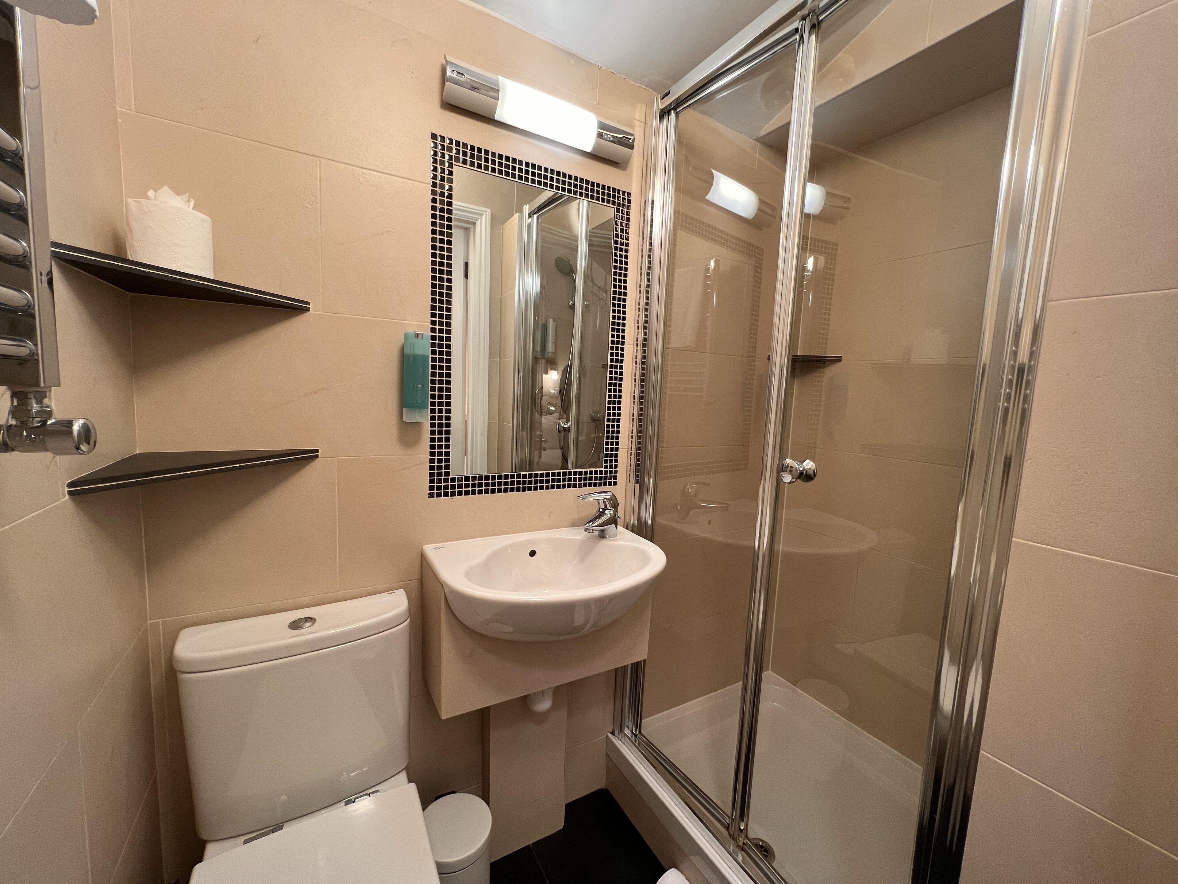 Une salle de bain équipée de toilettes, d’un lavabo et d’une douche à parois de verre.