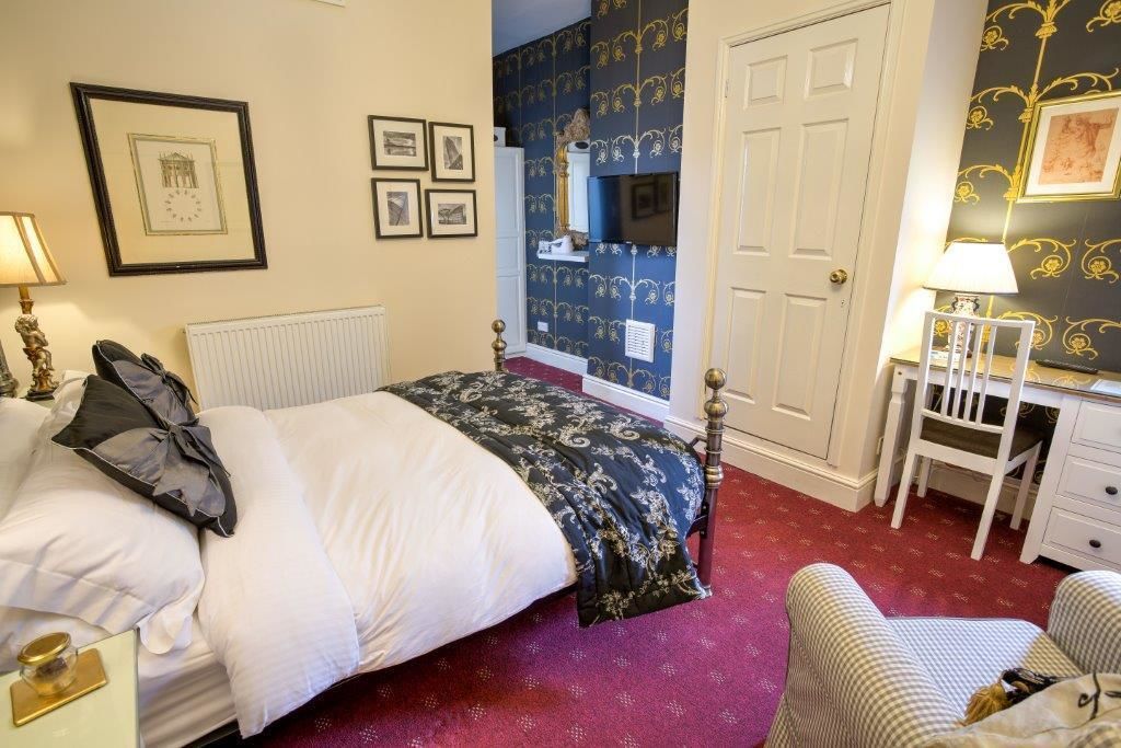 Una camera d'albergo con un letto, una sedia, una scrivania e un termosifone.